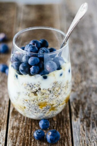 Blueberry Chia Overnight Oats in a small glass with fresh blueberries scattered around