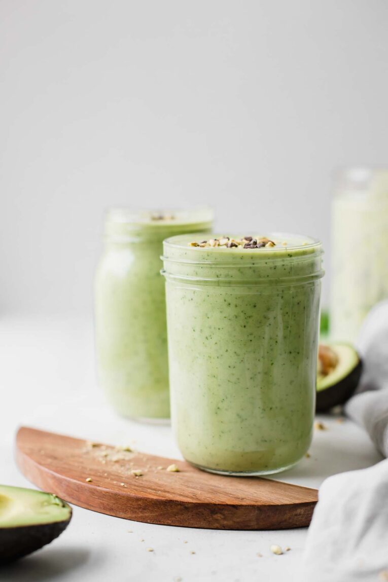 Two mason jars filled with avocado smoothie. 