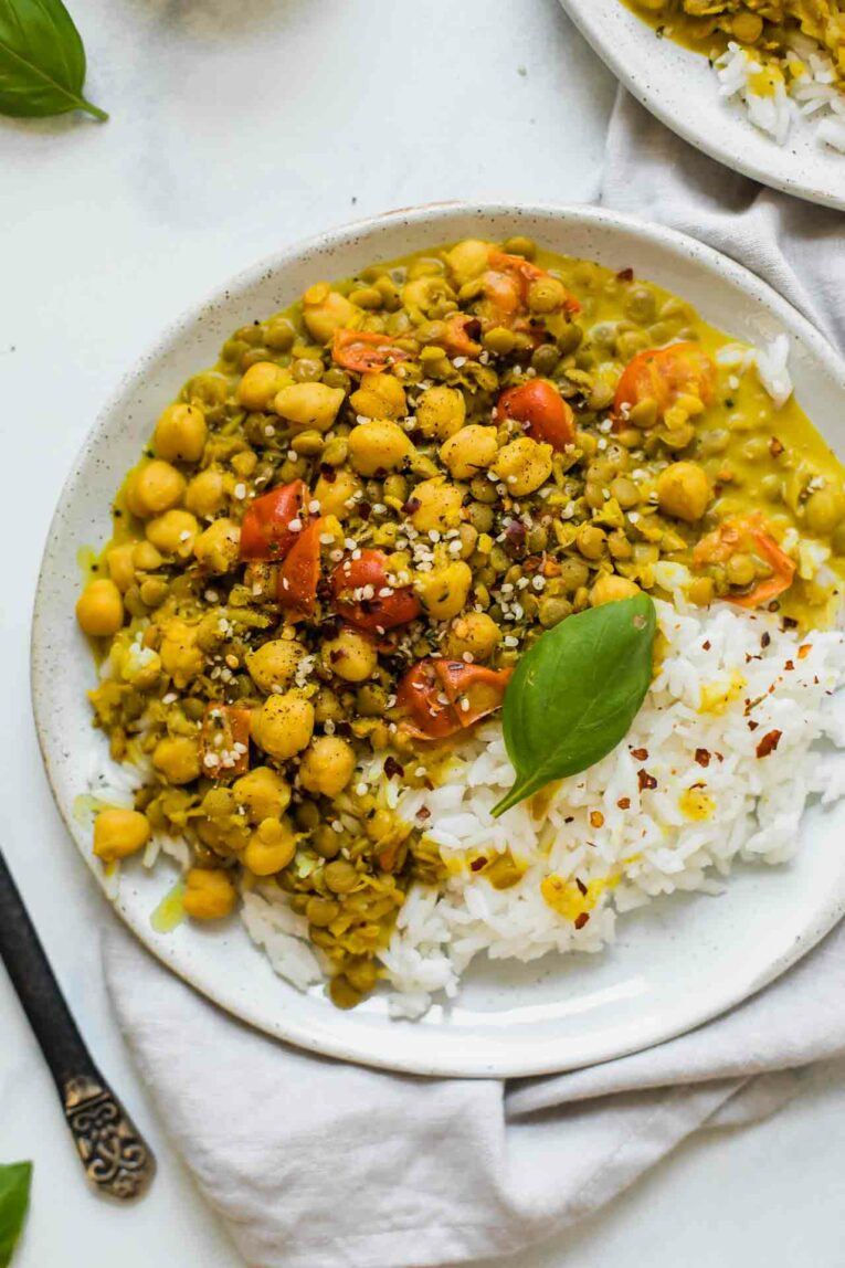 Chickpeas and lentils in a yellow curry sauce topped with peppers and served with rice.