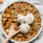 Healthy Apple Crisp in a tart dish with a wooden spoon.