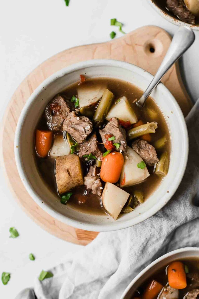 Top shot of beef stew in a white bowl with a spoon.