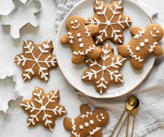 Gingerbread cookies spread across a marble countertop with cookie cutters and a plate.