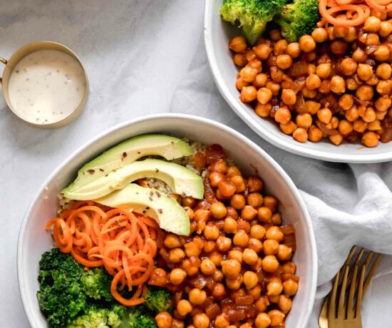 Two chickpea bowls with vegan buffalo sauce on a marble countertop.