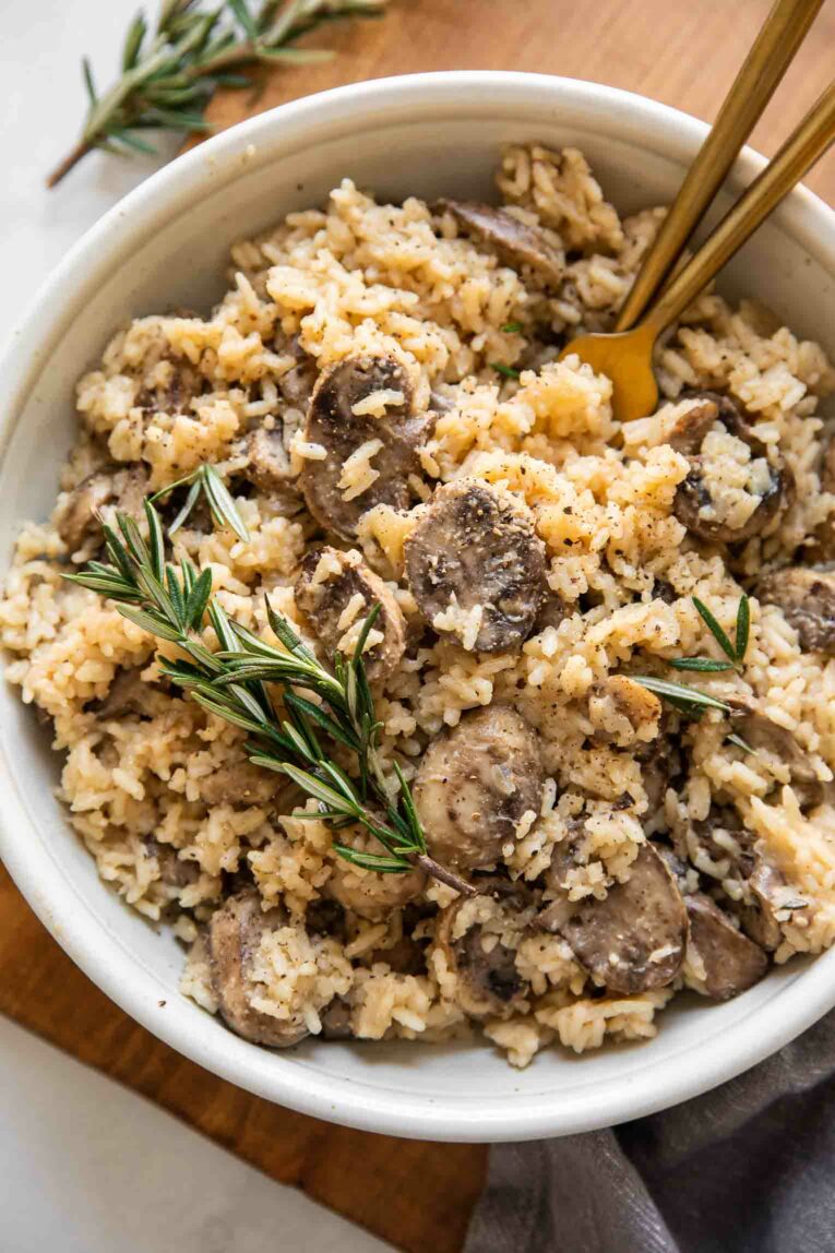 Rosemary Mushroom Rice Pilaf in a white bowl with two forks.