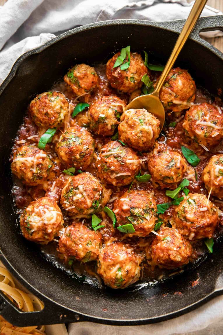 Top photo of baked spinach chicken meatballs with a red sauce.