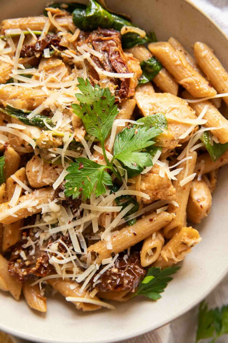 Close up image of penne pasta in a creamy tuscan sauce with sun-dried tomatoes and chicken.