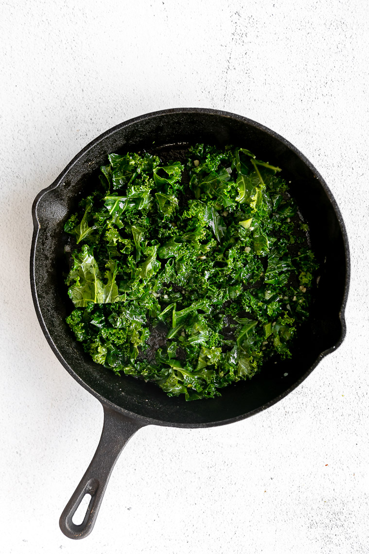 Kale being sautéed in a pan.