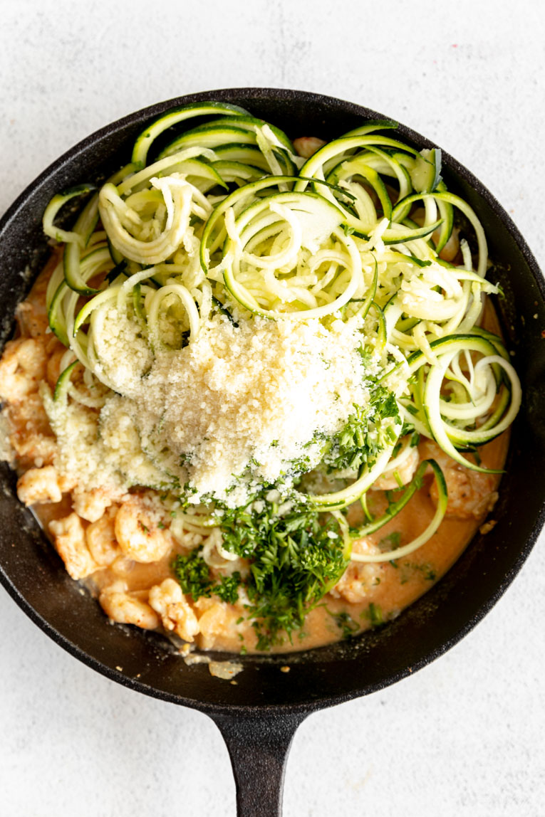 Zucchini noodles, parmesan, and shrimp in a skillet.
