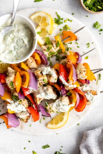 Greek Chicken Kabobs with tzatziki sauce on a platter.