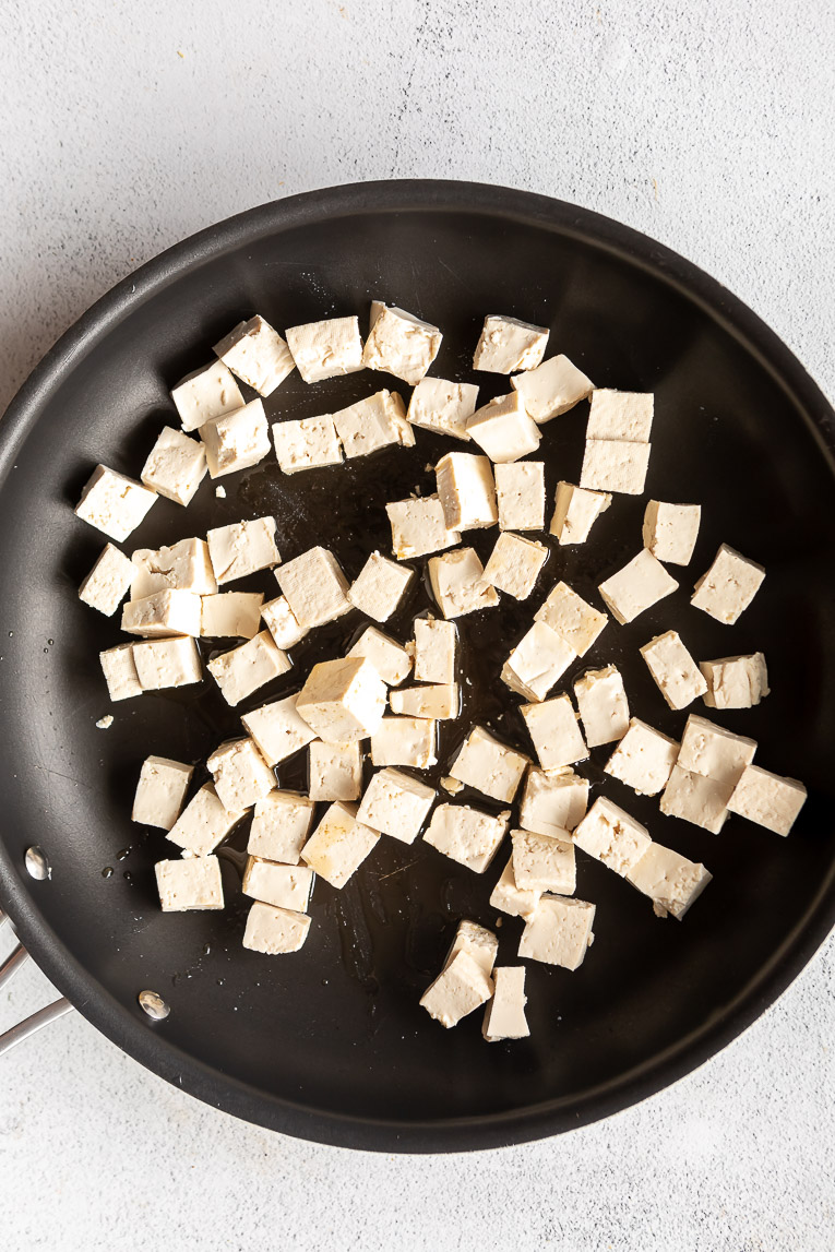 Cubed firm tofu in a skillet.