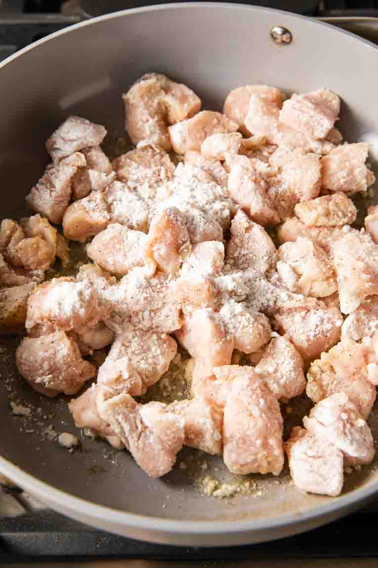 Chicken being sautéed with cornstarch and oil.