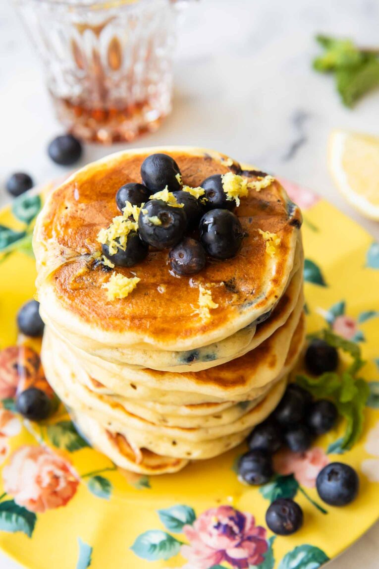 Angled image of A stack of lemon blueberry muffins on a plate.